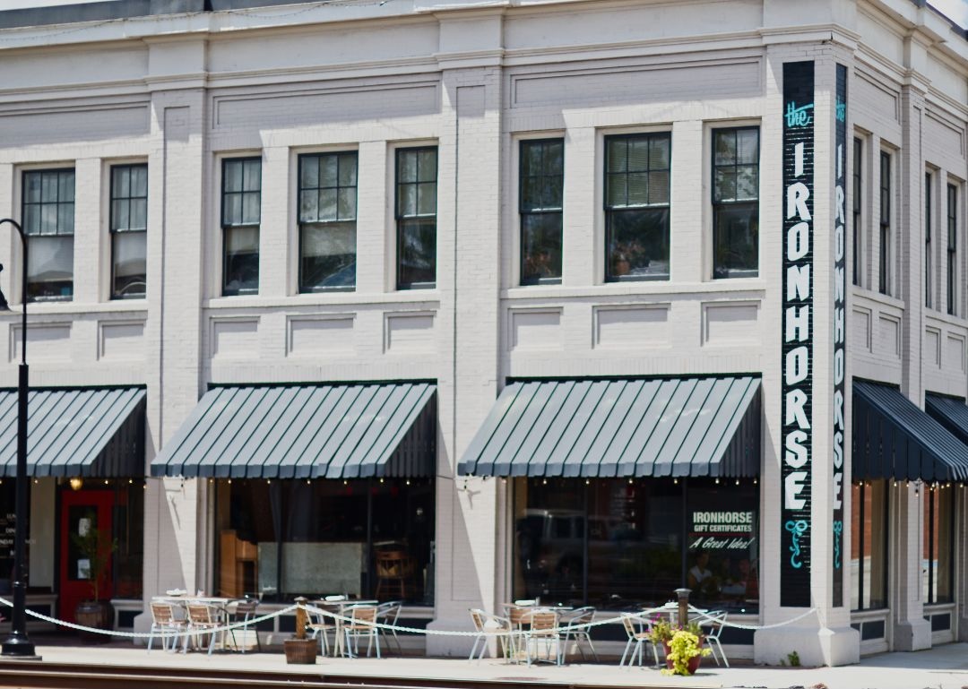 Store Banne à Projection 4 Accouplement de stores à rayures vert-forêt et blanches sur immeuble blanc de grand standing avec moulures